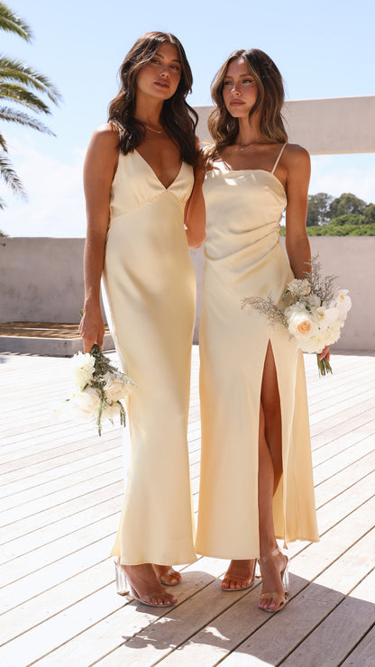 Two women in cream ruched maxi dresses with V-neck and slit