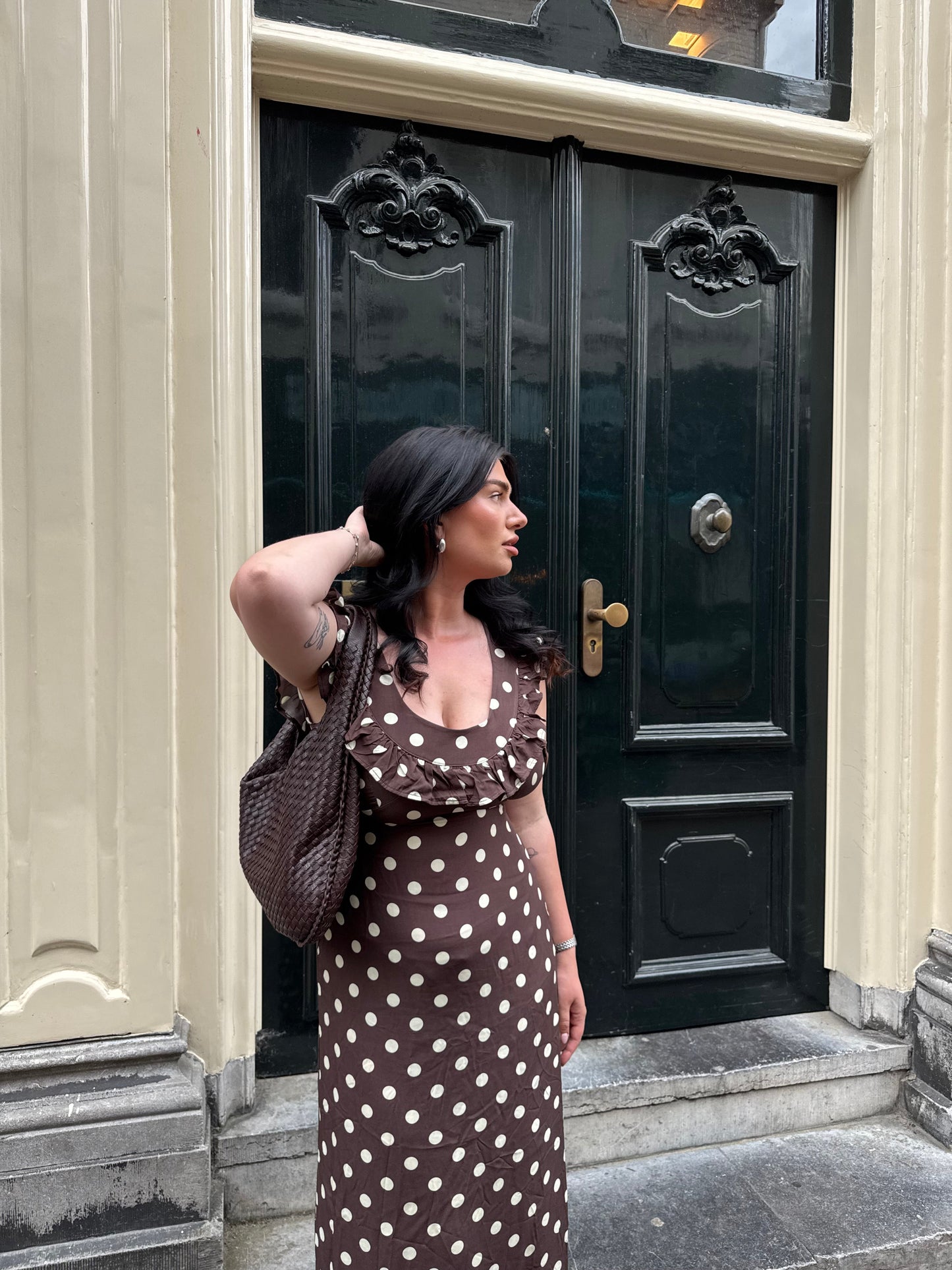 Brown polka dot maxi dress with ruffle sleeves worn with crossbody bag