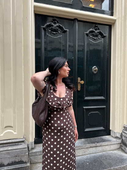 Brown polka dot maxi dress with ruffle sleeves worn with crossbody bag