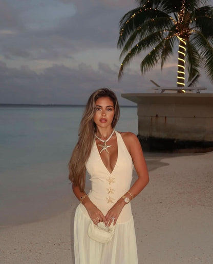 Cream halter maxi dress with starfish details on beach at sunset