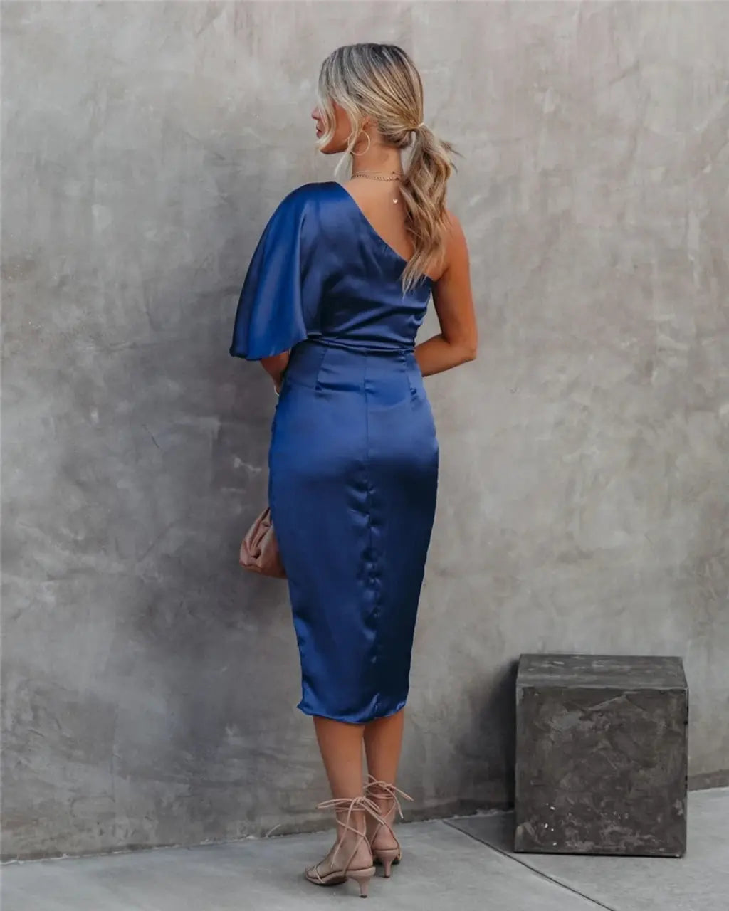Back view of navy blue draped midi dress with flutter cape sleeve and fitted ruched bodice