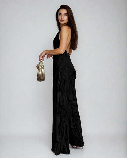 Side view of black pleated pants set showing backless halter design and draped silhouette