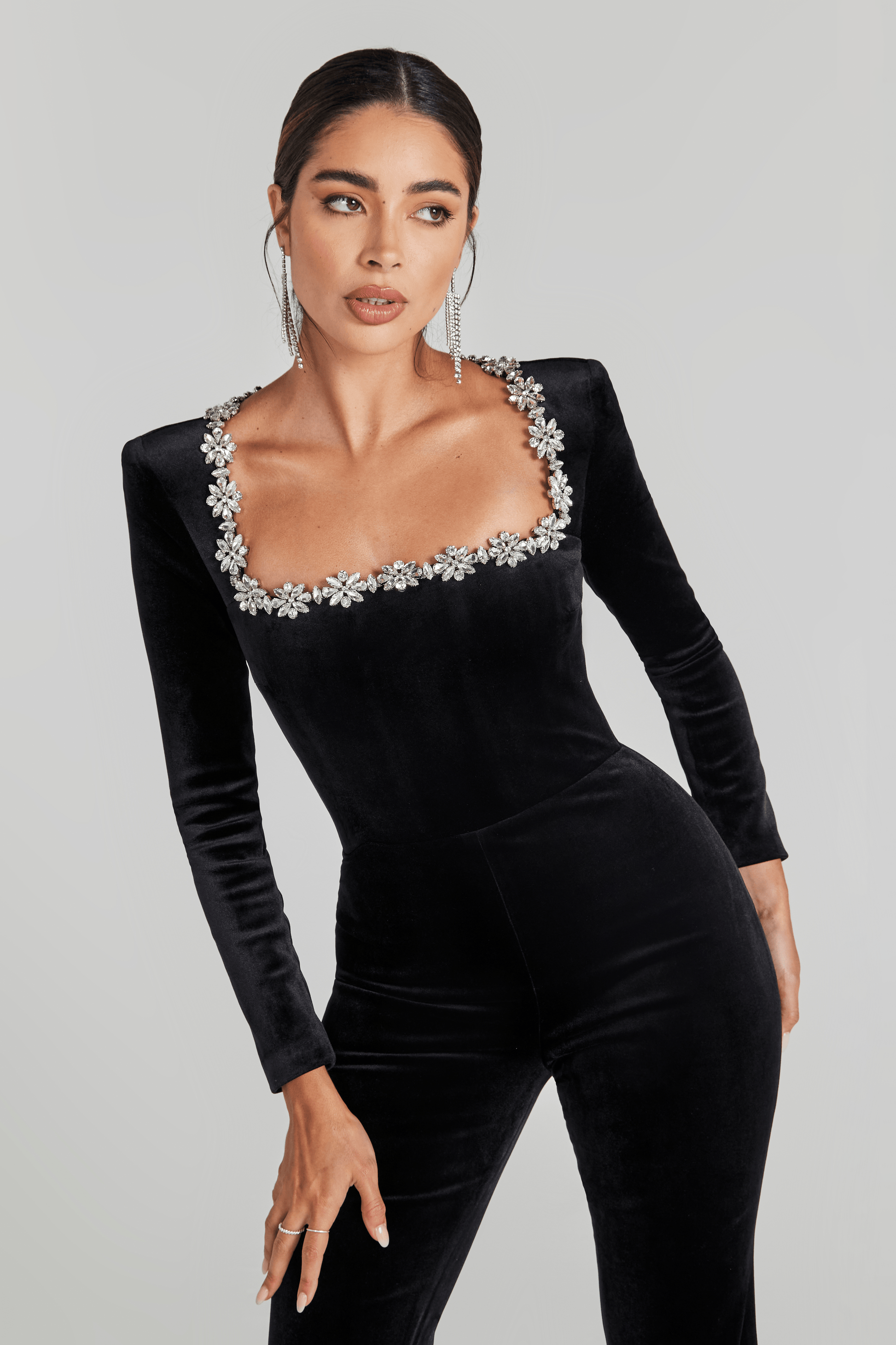 Close-up of black velvet jumpsuit featuring square neckline trimmed with sparkling crystals