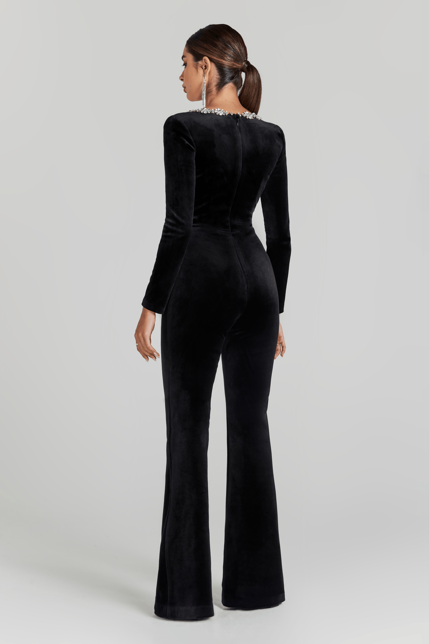 Back view of black velvet jumpsuit with flared legs and crystal-trimmed square neckline