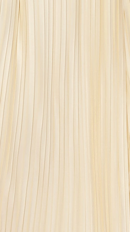 Close-up of cream vertical pleated fabric texture on maxi dress