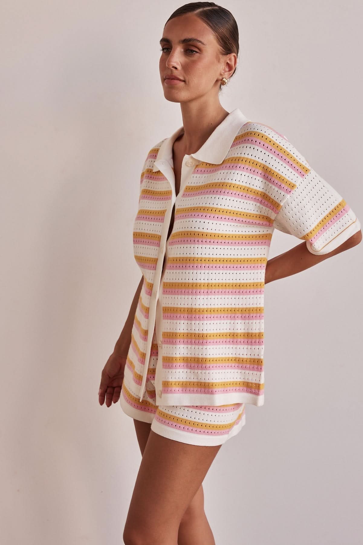 Side view of women's striped matching shorts set with pink and orange horizontal stripes