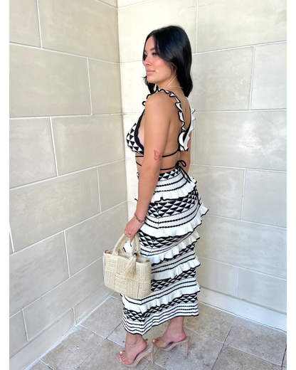 Side profile of geometric knit set showing cross-back crop top and tiered midi skirt detail