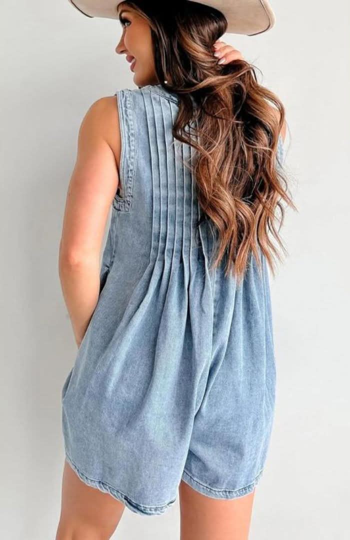 Light blue denim romper back view showing pleated panel and pocket detail