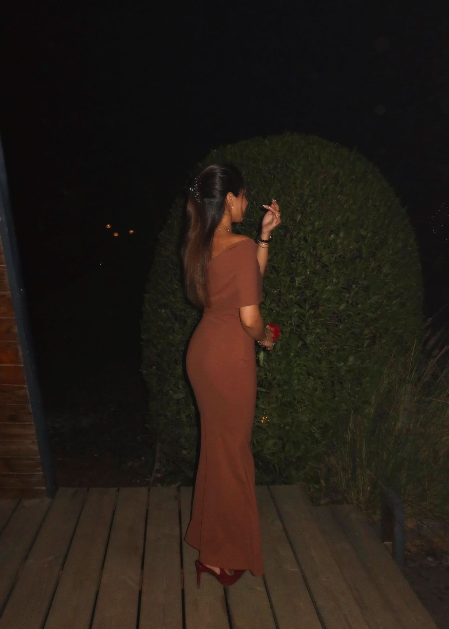 Back view of rust fold-over maxi dress showing draped shoulder and fitted back
