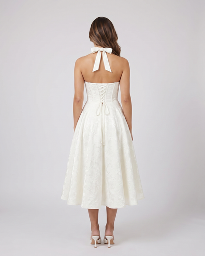 Back view of ivory floral jacquard halter midi dress showing lace-up corset back with halter tie-back forming a bow