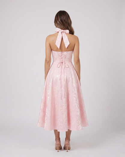Back view of pink floral jacquard halter midi dress showing lace-up corset back with halter tie-back forming a bow