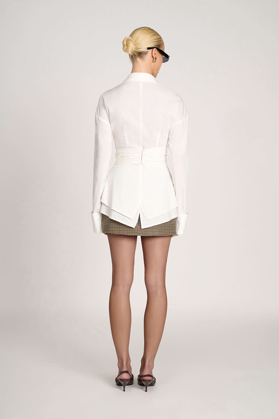Back view of white ruched collared top with gathered waist detail