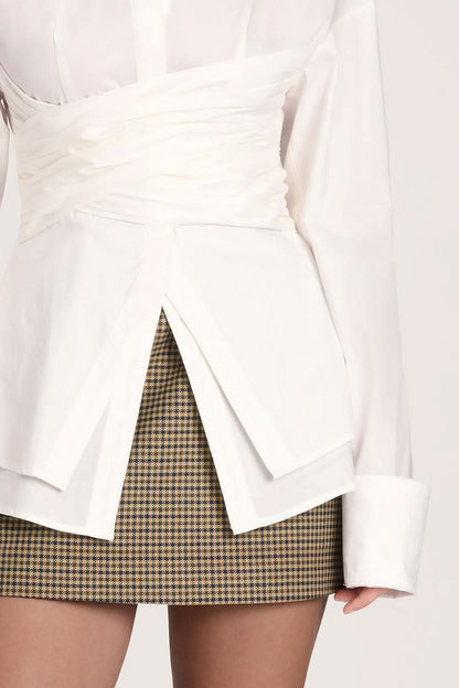 Close-up of white collared top showing ruched wrap waist and slit