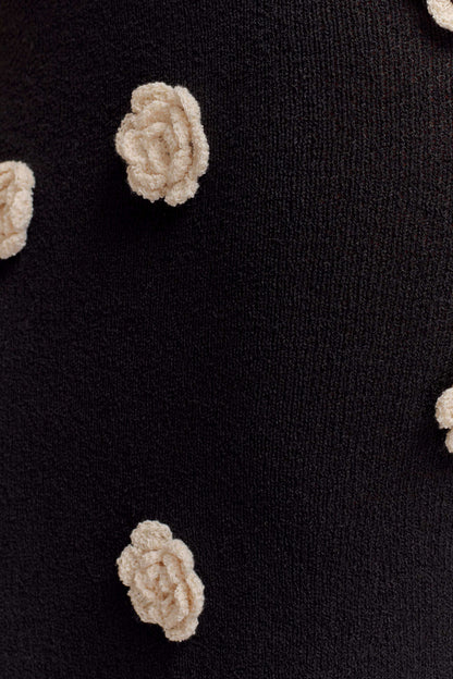 Close-up of cream textured rose appliqués on black knit fabric