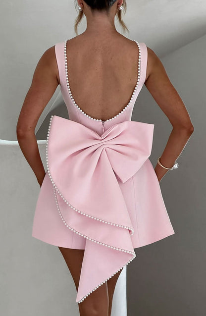 Blush pink mini dress with pearl-beaded back and oversized bow detail