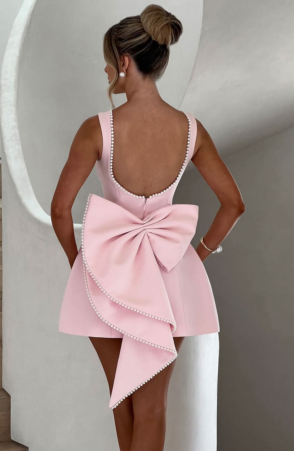 Black mini dress with pearl-beaded back and dramatic bow detail