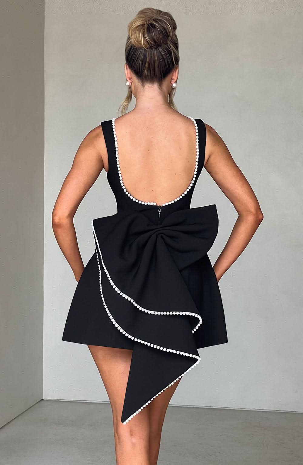 Black sleeveless mini dress with pearl neckline and fitted silhouette
