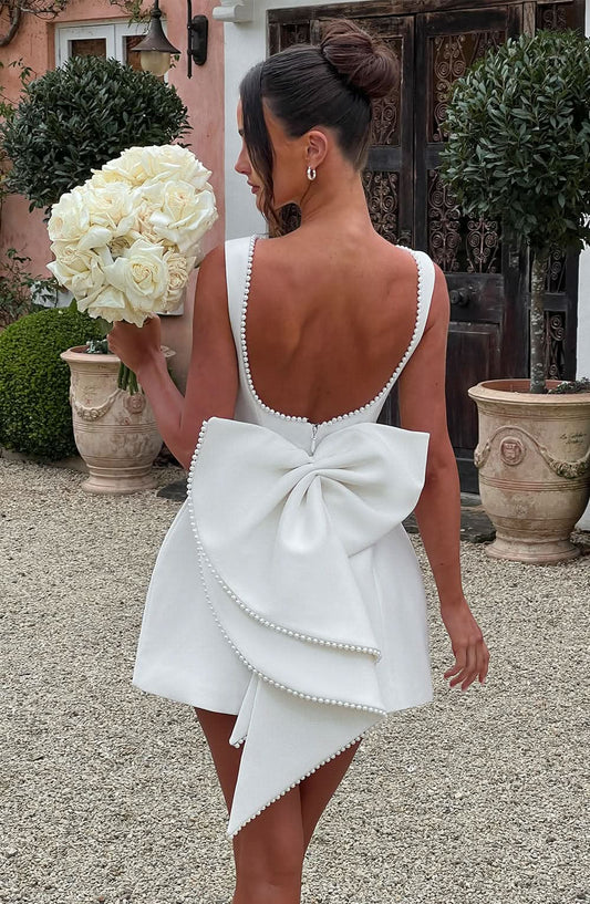 White mini dress with pearl-trimmed back bow and open back detail